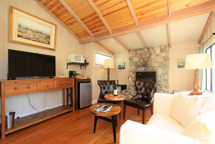 carmel lodging - room with couch, stone fireplace and TV