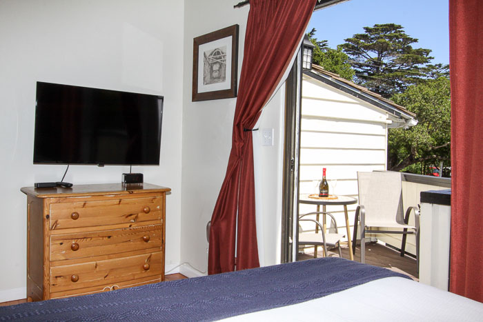 room with bed, TV, dresser and outdoor deck with chairs