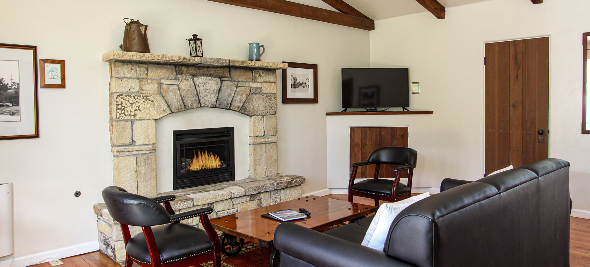 living room with stone firesplace, couch, TV and wood floor